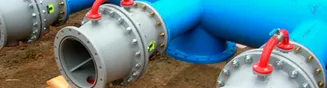 Válvulas de gran diámetro con volantes rojos acopladas a tuberías azules, antes del montaje.