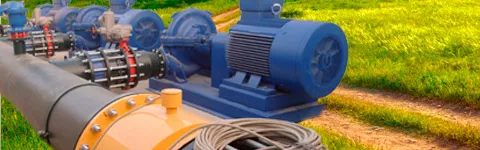 Grupos de bombeo azules conectados a una tubería de gran diámetro, junto a un campo de cereal.