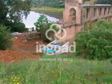Obra de toma al pie de una presa, con tuberías azules en un cajero de hormigón.