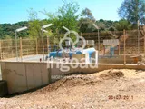 Caseta de bombeo vallada sobre un muro de hormigón, con tuberías y cuadros eléctricos.